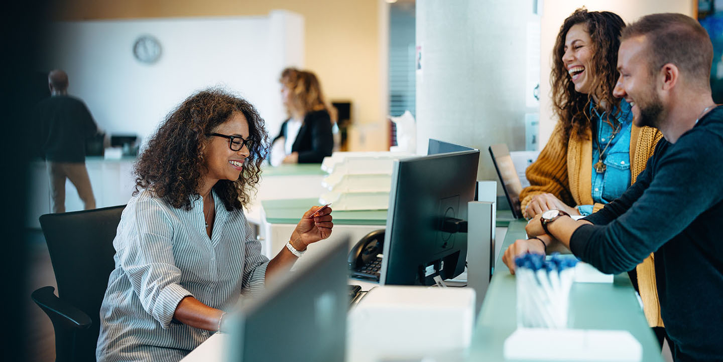 Receptionist assisting people standing at front desk